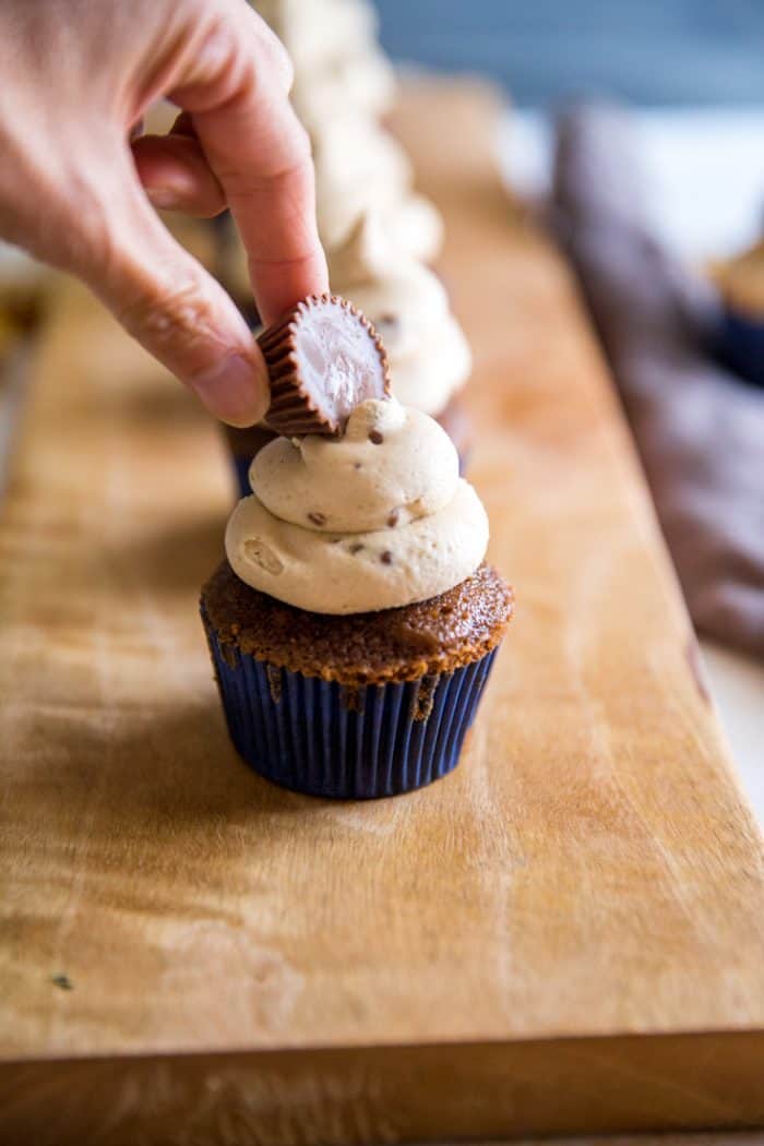 hand putting peanut butter cup on peanut butter frosting