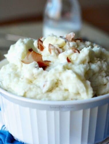 Small white bowl of Pancetta Blue Cheese Buttermilk Mashed Potatoes with bacon bits and butter.