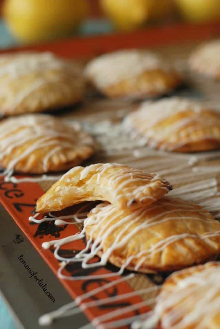 lemon hand pies on a baking sheet, one with a bite taken out