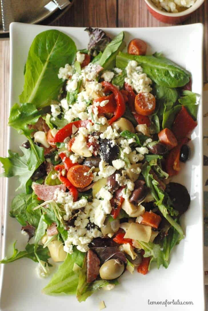 A simple antipasto salad with two kinds of olives, roasted red peppers, artichokes and a tangy feta vinaigrette www.lemonsforlulu.com