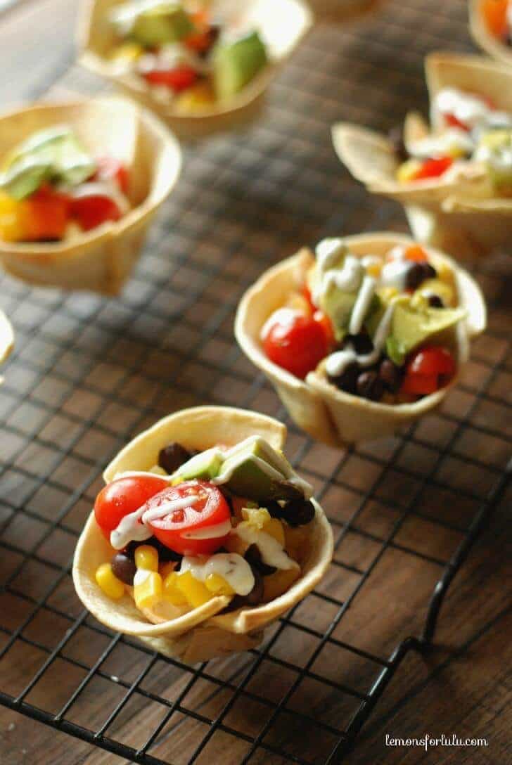 Mini tortilla cups filled with a taco flavored cream cheese, black beand and lots of veggies! www.lemonsforlulu.com