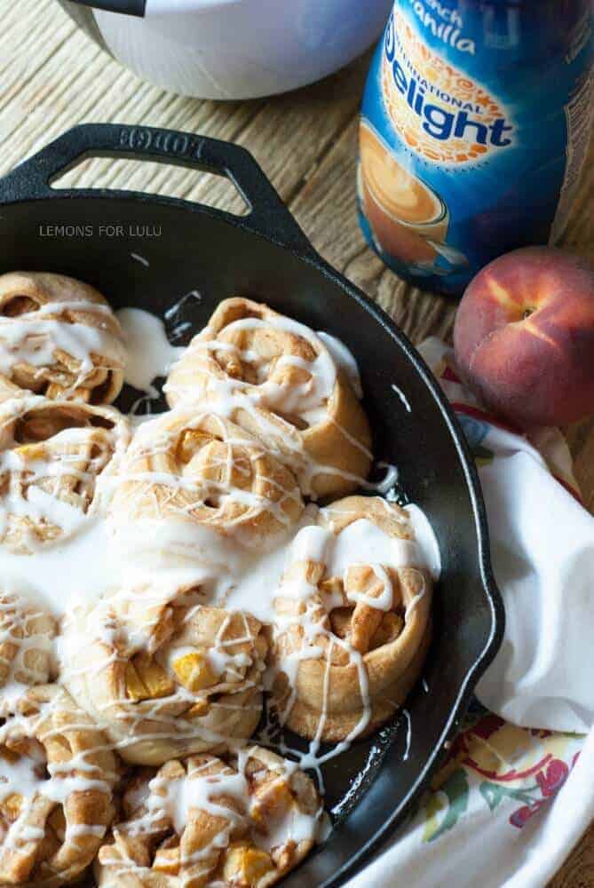 This cinnamon roll recipe is so easy, you will fall in love! A cast iron skillet, fresh peaches and crescent roll dough makes them irresistible! www.lemonsforlulu.com