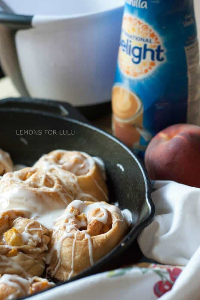 This cinnamon roll recipe is so easy, you will fall in love! A cast iron skillet, fresh peaches and crescent roll dough makes them irresistible! www.lemonsforlulu.com
