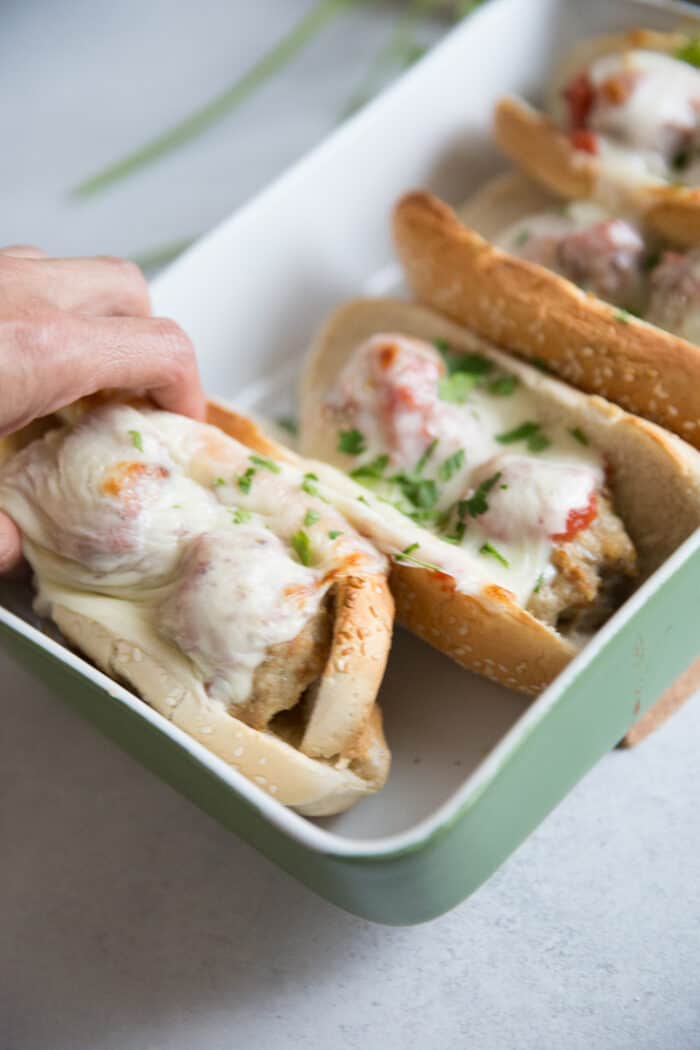 Hand reaching for a meatball sub