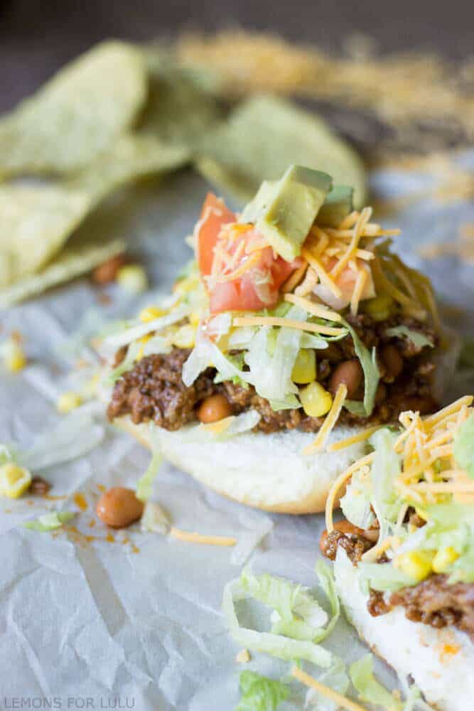 Easy and simple taco sloppy joes with fresh avocado, cheese, sweet corn and tomatoes.