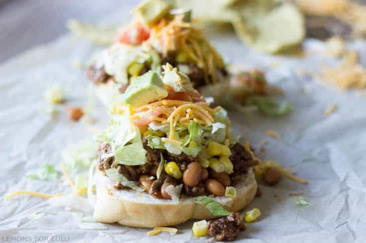 Delicious sloppy joes turned into tacos on parchment paper and topped with sweet corn, lettuce, cheese and tomatoes.