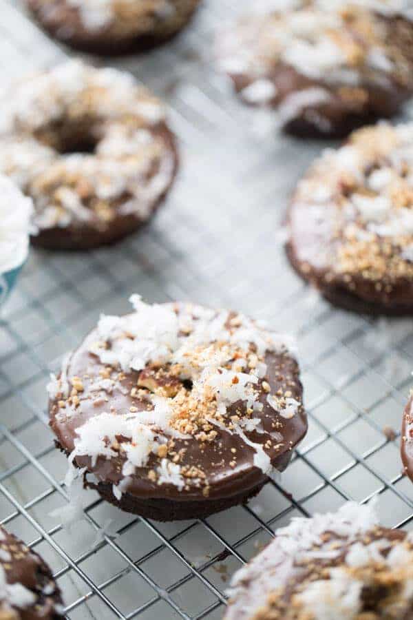Chocolate donuts are baked in the oven then dipped in a smooth chocolate glaze and covered in coconut and almonds to taste just like the favorite almond coconut candy bar! lemonsforlulu.com