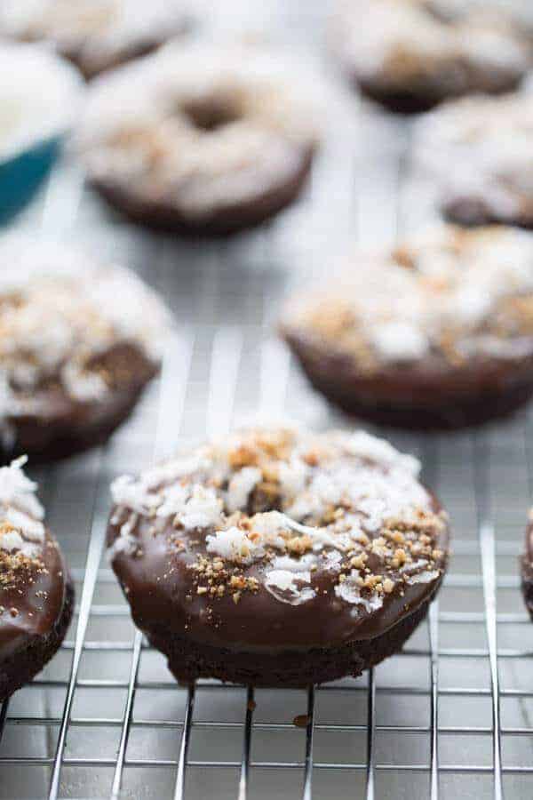 Chocolate donuts are baked in the oven then dipped in a smooth chocolate glaze and covered in coconut and almonds to taste just like the favorite almond coconut candy bar! lemonsforlulu.com