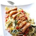 This salmon topped pasta Primavera is filled with veggies and tossed with a light, creamy sauce. A simple, elegant meal for any occasion. lemonsforlulu.com