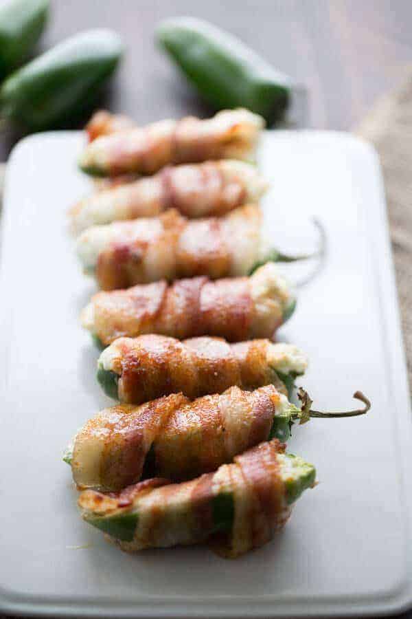 Seven delicious cheese stuffed jalapeños on a white platter.