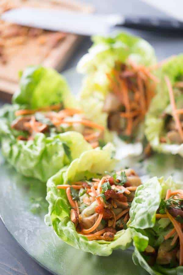These chicken lettuce wraps are such an easy recipe to make! Soy and ginger glazed chicken is surrounded by bibb lettuce and topped with chopped cucumber, shredded carrots and spicy Srirach almonds! lemonsforlulu.com