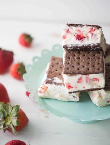 A homemade strawberry ice cream recipe spread between two chocolate graham crackers for a fun take on ice cream sandwiches! lemonsforlulu.com