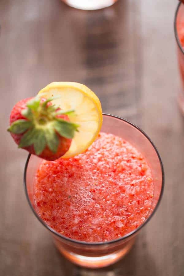Non alcoholic Strawberry Rickey Drink in a small glass with a delicious strawberry and slice of lemon.