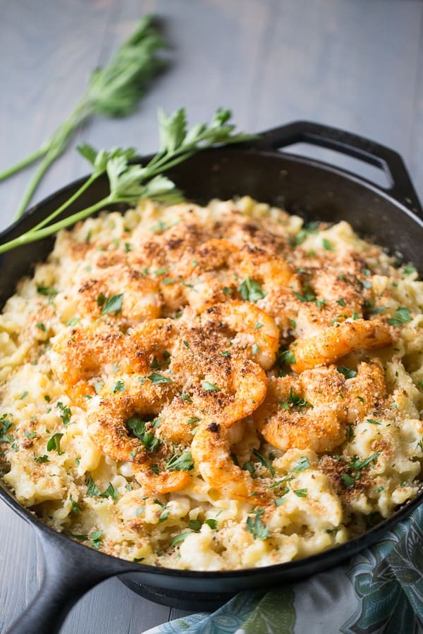 Cast iron skillet with Cajun Shrimp Mac and Cheese on a wooden table.