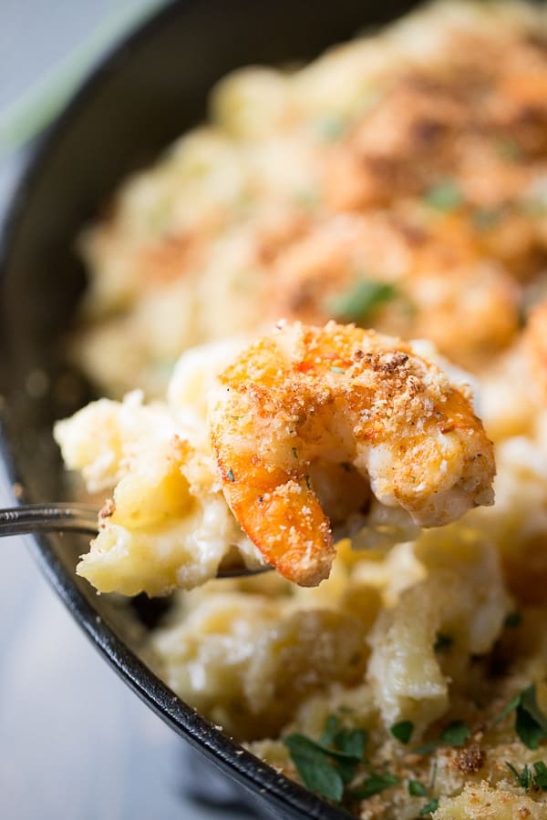 Scooping a bite of Cajun Shrimp Mac and Cheese out of a black cast iron skillet.