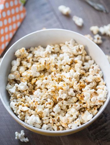 Delicious kettle corn with sugar and BBQ seasoning in a large white bowl on a wooden table.