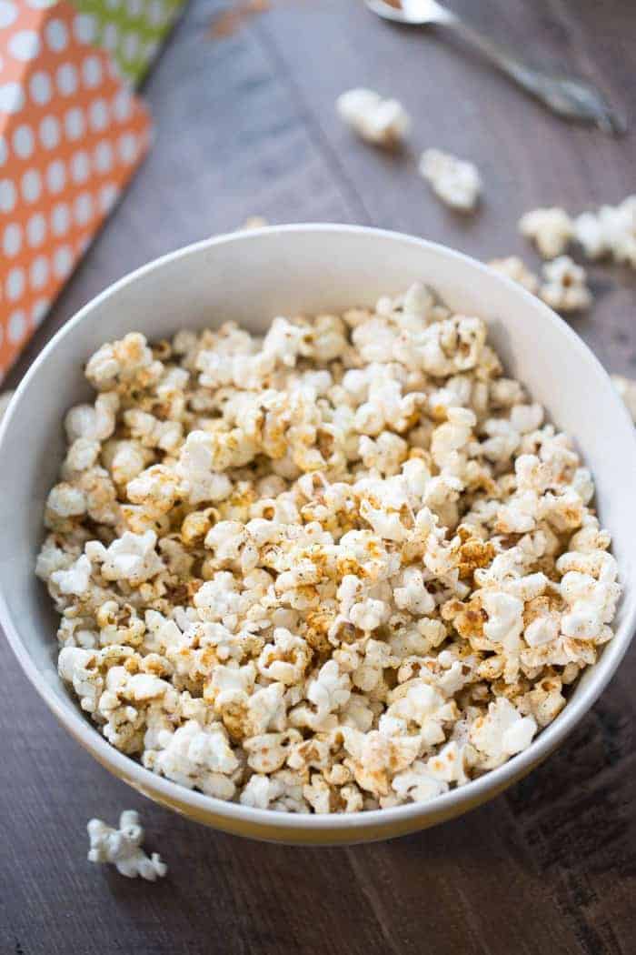 Homemade kettle corn recipe served with a sprinkling of BBQ seasoning in a large white bowl on a wooden table.