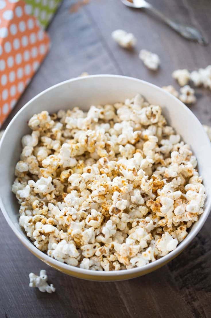 Delicious kettle corn with sugar and BBQ seasoning in a large white bowl on a wooden table.