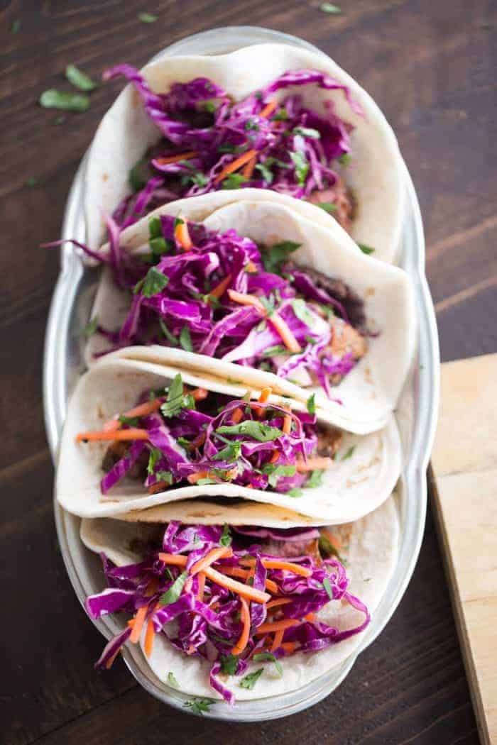 Grilled steak tacos have a fusion flair! Ginger infused cabbage and garlic beans make these tacos full of flavor!
