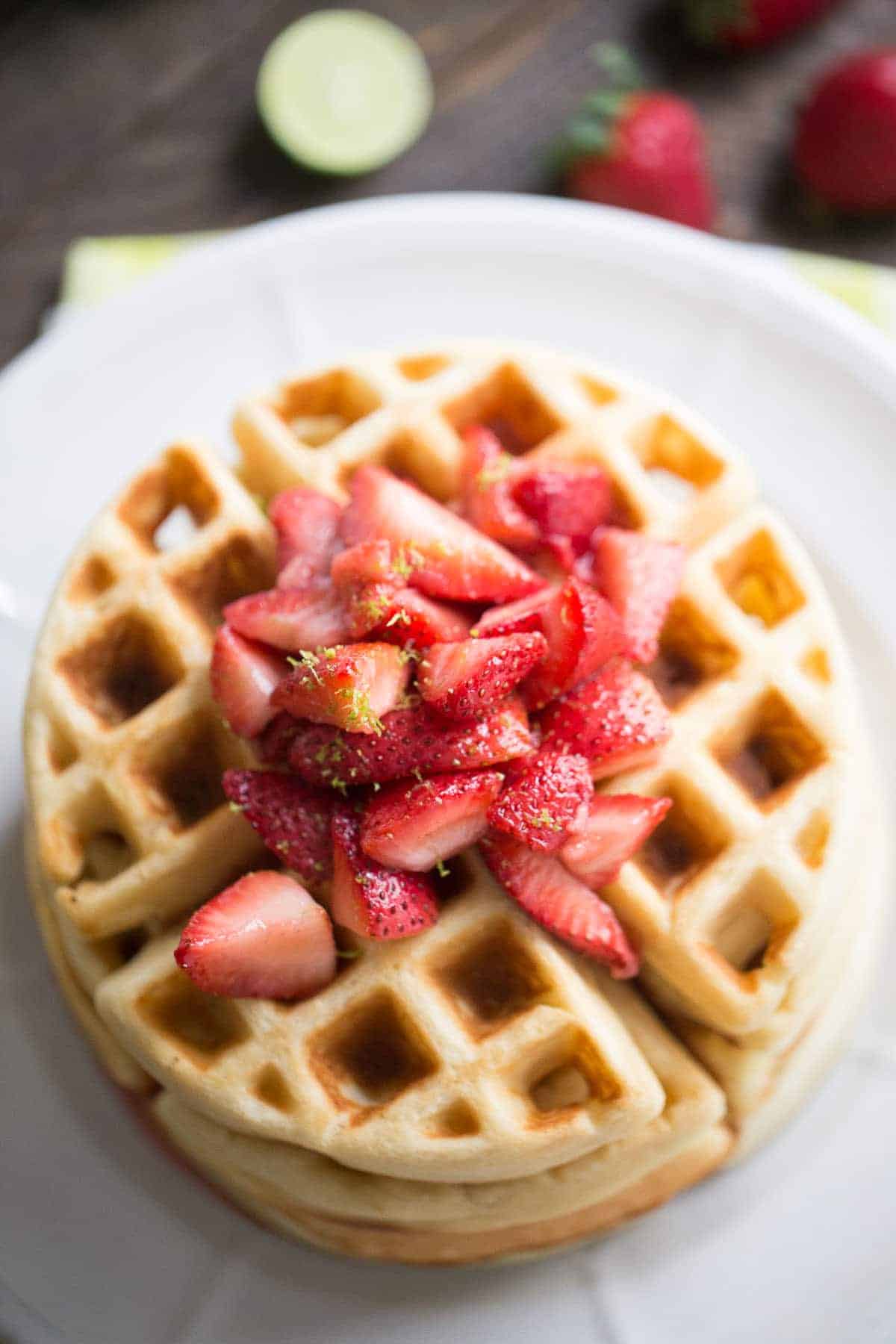 This easy homemade waffles recipe gets a tangy kick from key lime and is served with a sweet strawberry topping.