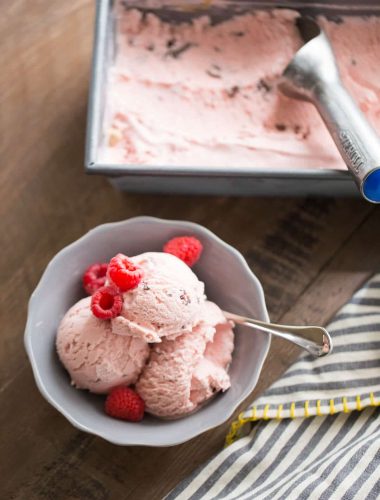 Chocolate swirled raspberry ice cream with raspberries in a small grey bowl.