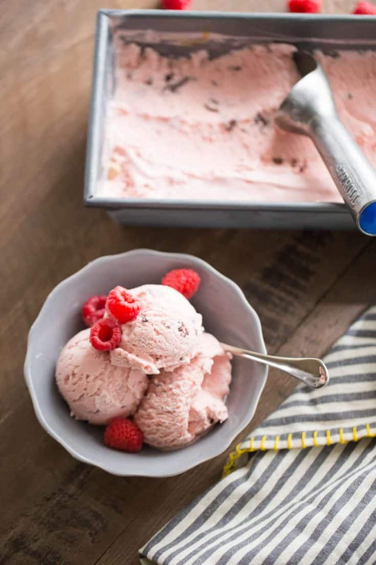 Chocolate swirled raspberry ice cream with raspberries in a small grey bowl.
