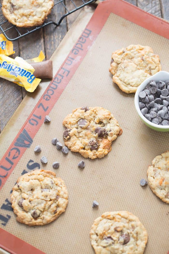 Four simple Butterfinger cookies surrounded by chocolae chips and an unwrapped Butterfinger.