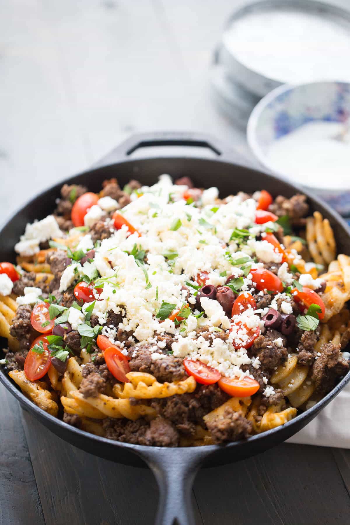 Loaded Greek fries in a cast iron skillet