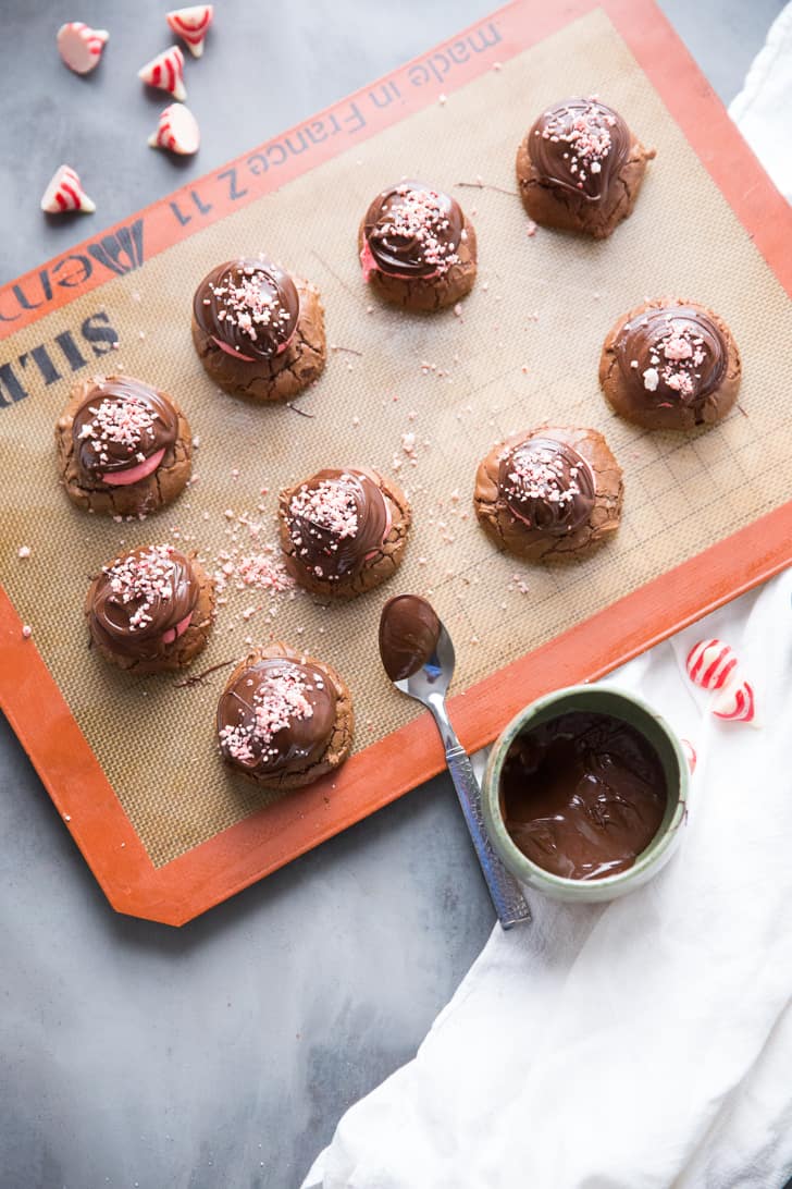 Nine Chocolate Mint Cookies on a baking tray with a small bowl of chocolate frosting.