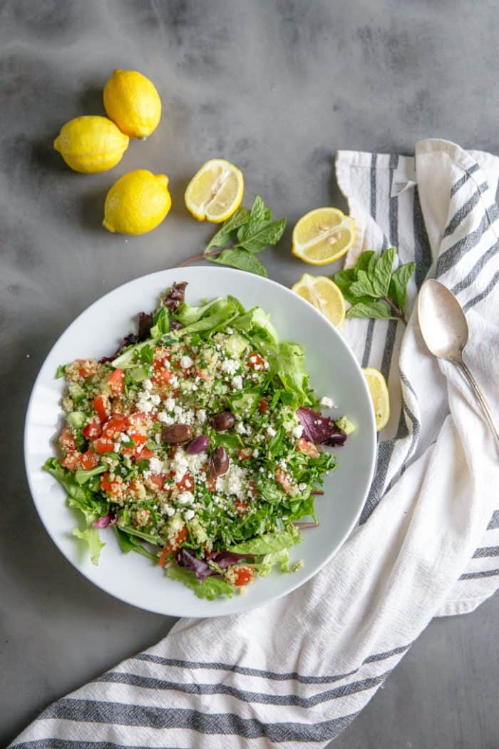 quinoa tabbouleh in a bowl surrounded by lemons
