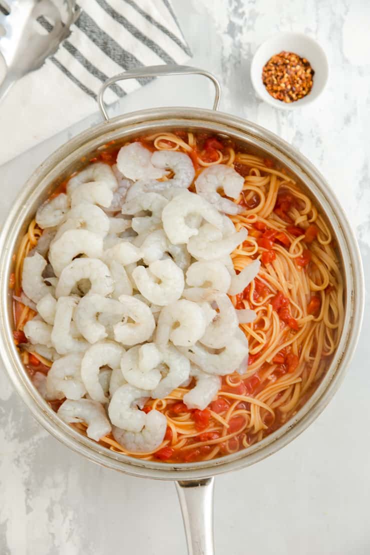 raw shrimp being added to pasta