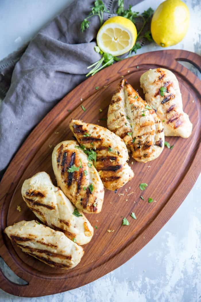 Grilled chicken on wooden tray with lemons