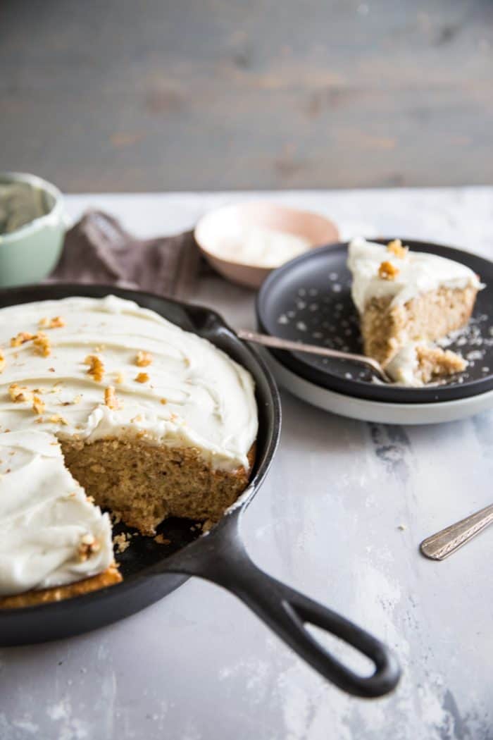 Hummingbird cake in skillet with one black plate