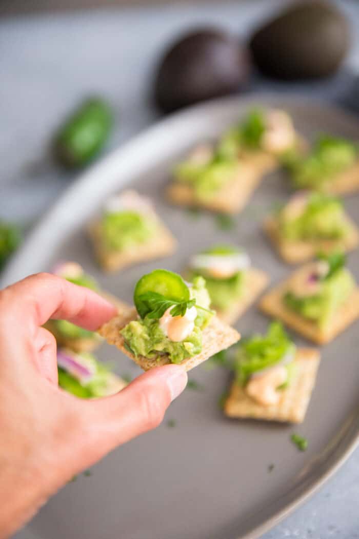 held Triscuit with avocado
