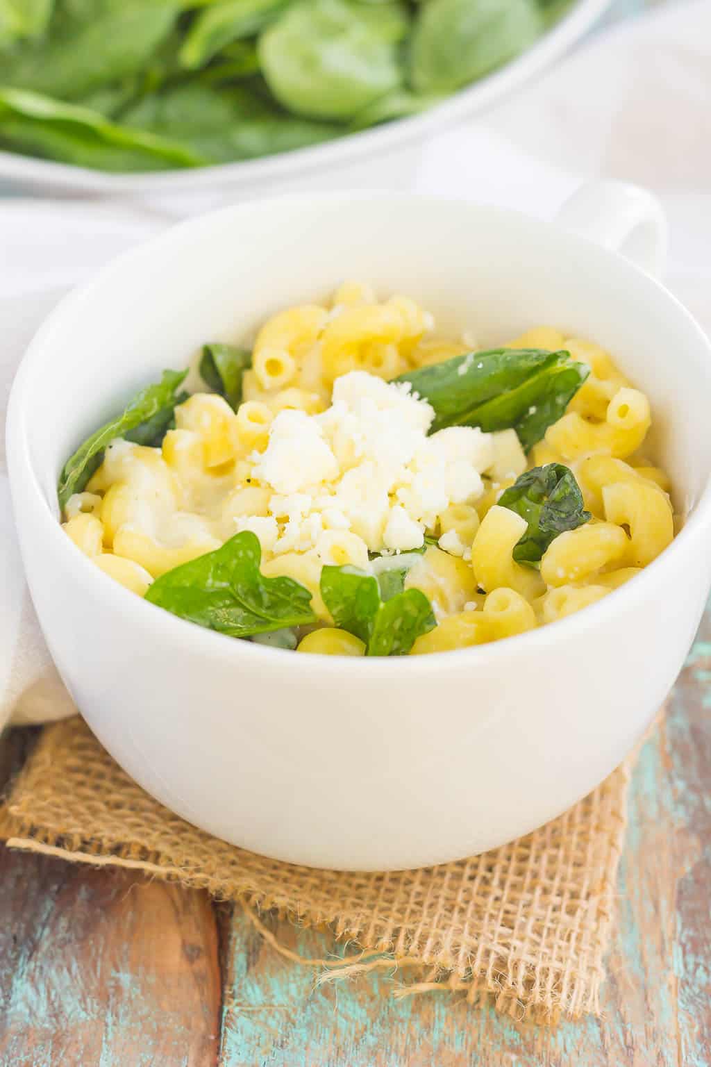 A bowl of food on a plate, with Cheese and Macaroni