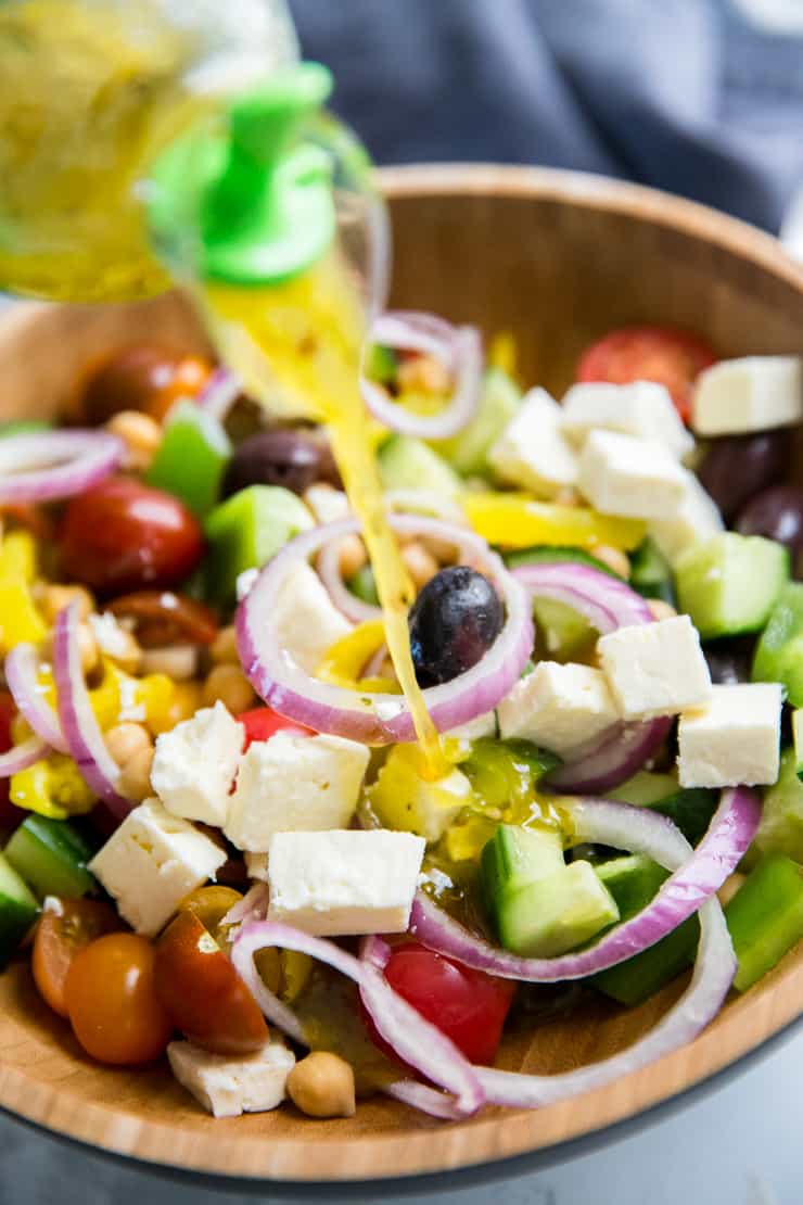 salad dressing poured over Greek salad