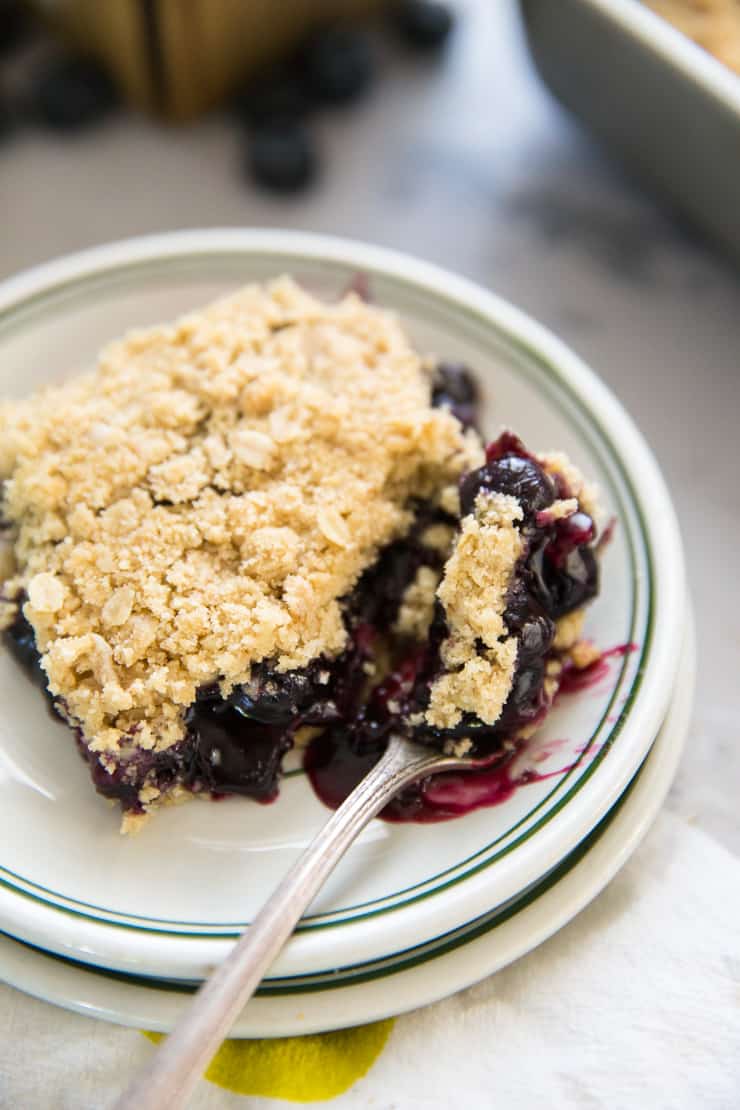 one slice of blueberry oatmeal bars with a fork taking a bite