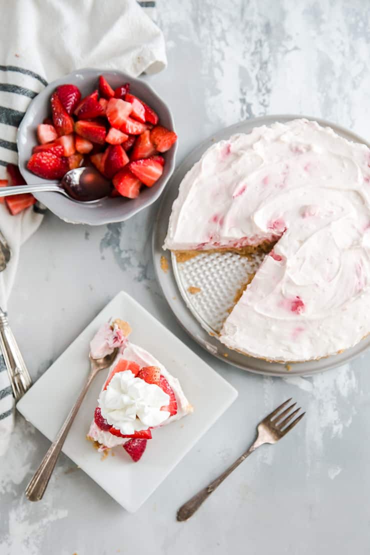 no bake cheesecake with strawberries and a slice on the side with forks