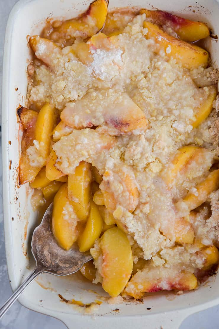 baked peach cobbler with a serving spoon