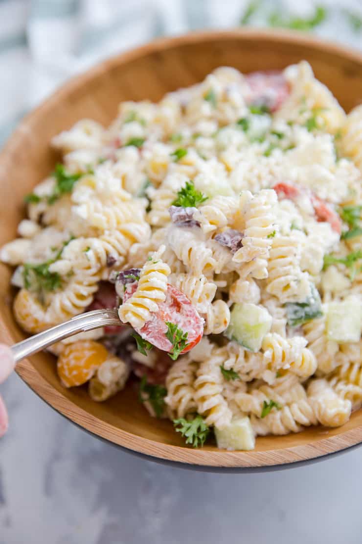 Greek pasta salad with a spoon serving it up