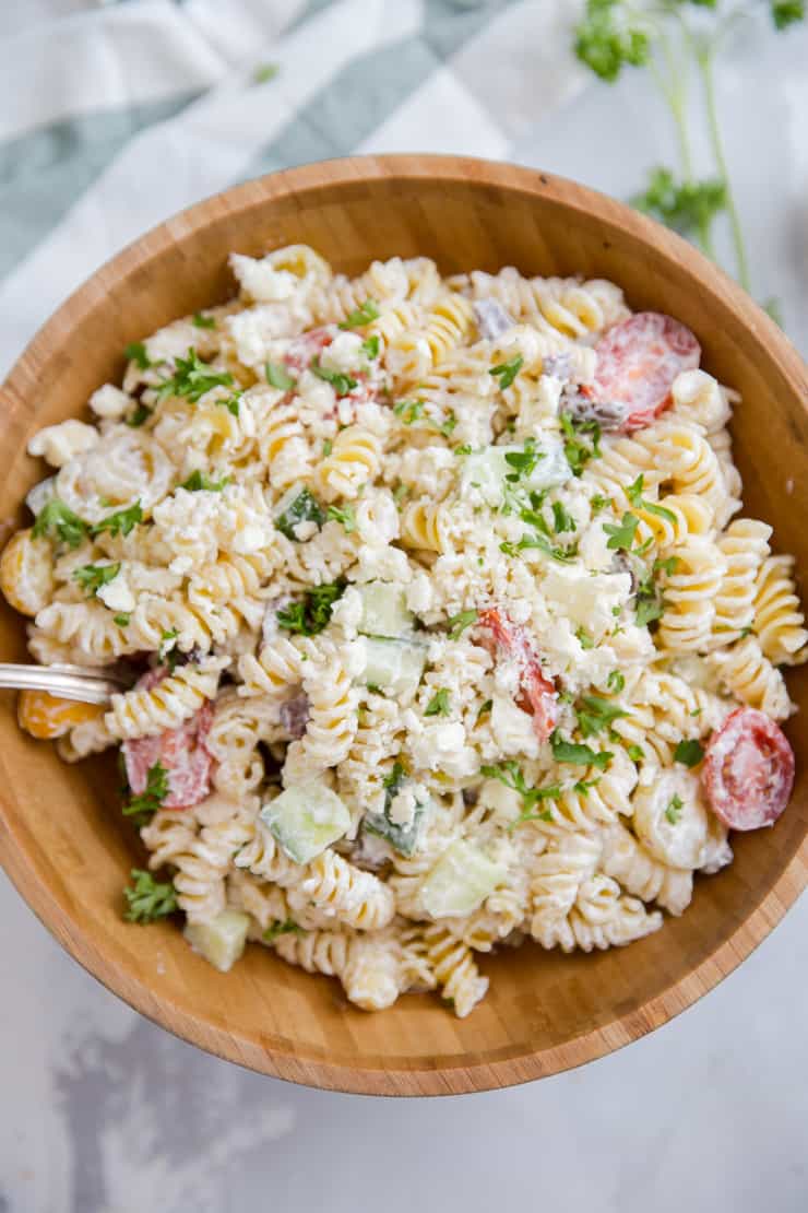 Greek pasta salad with a spoon resting in the bowl