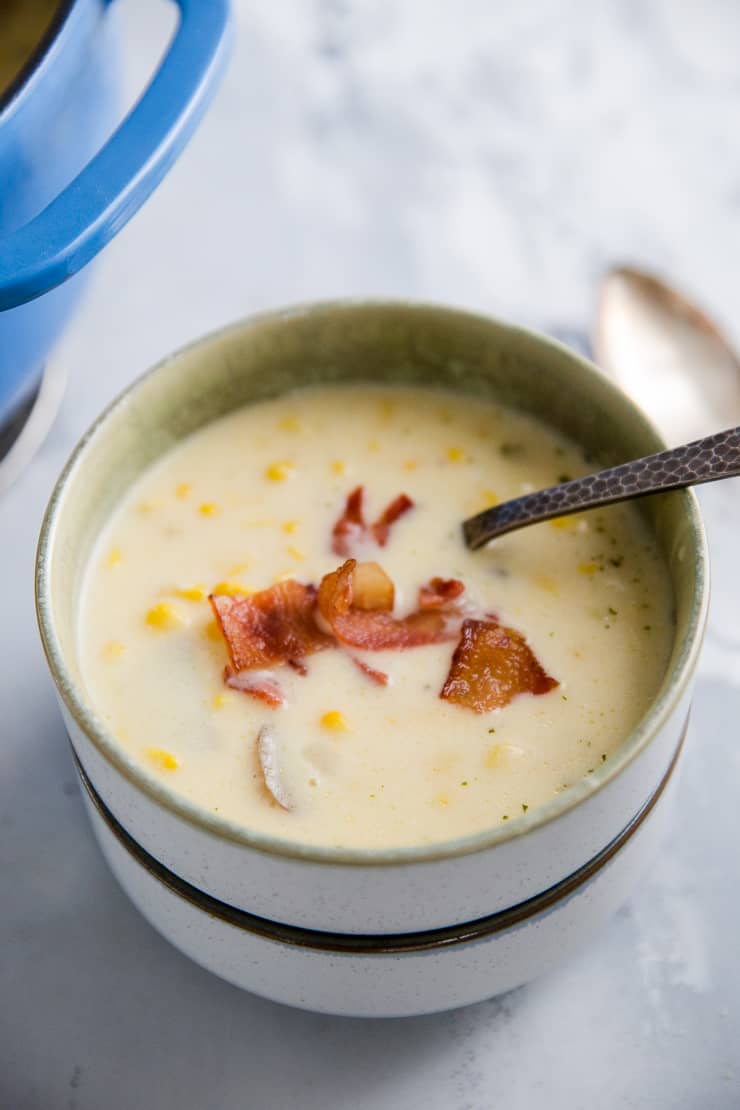 corn chowder in a bowl with a spoon and bacon pieces as garnish