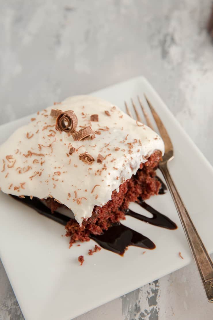 poke cake on a white plate with chocolate sauce