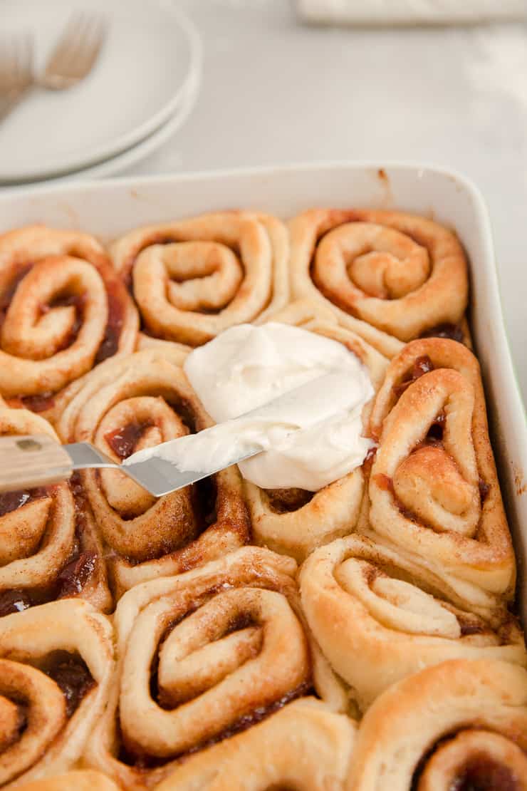 Cinnamon rolls getting frosted