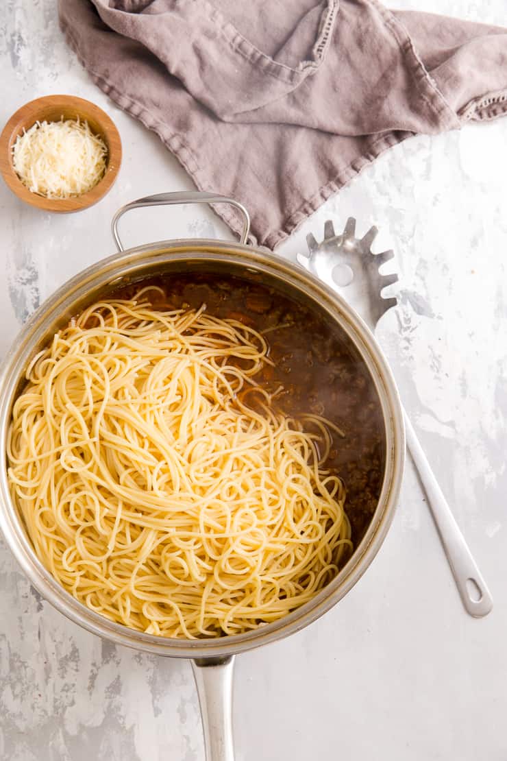 spaghetti in a pan of ragu sauce