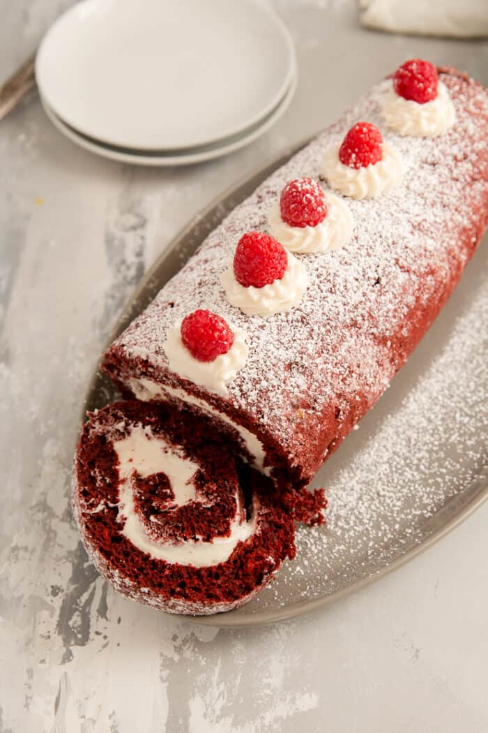 red velvet cake roll with a slice laying down