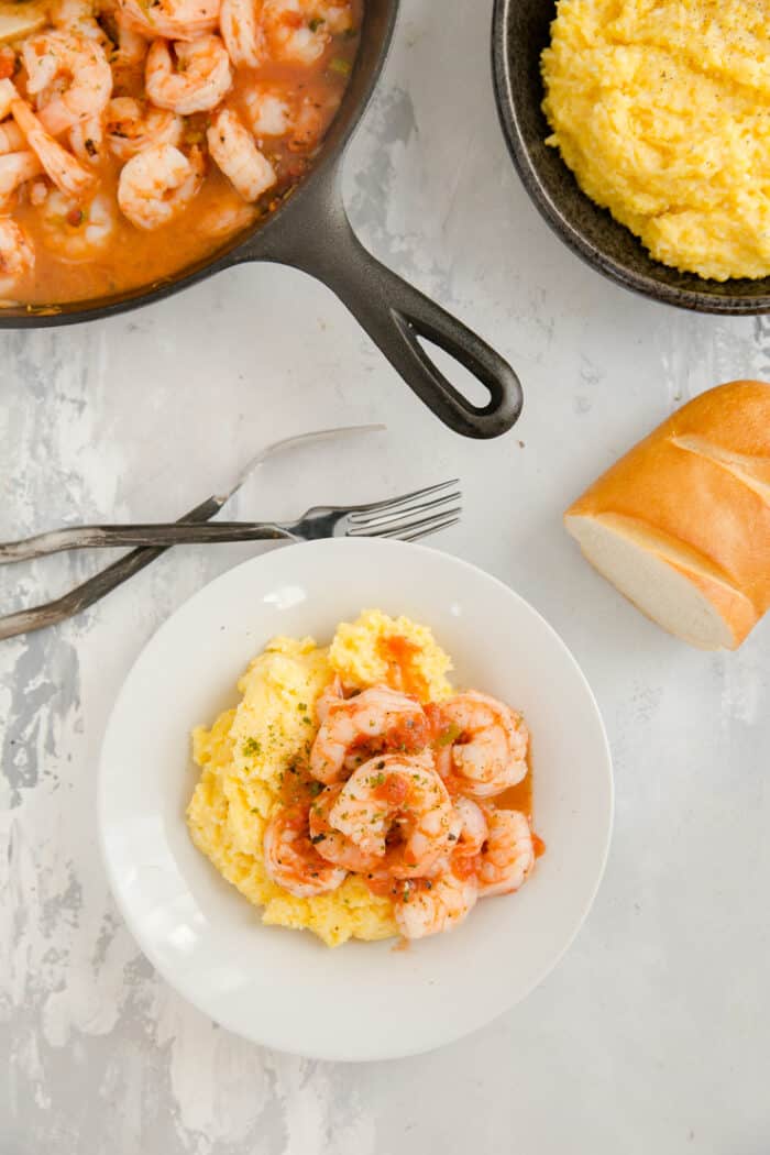 bowl of shrimp and grits with bread and the skillet on the side