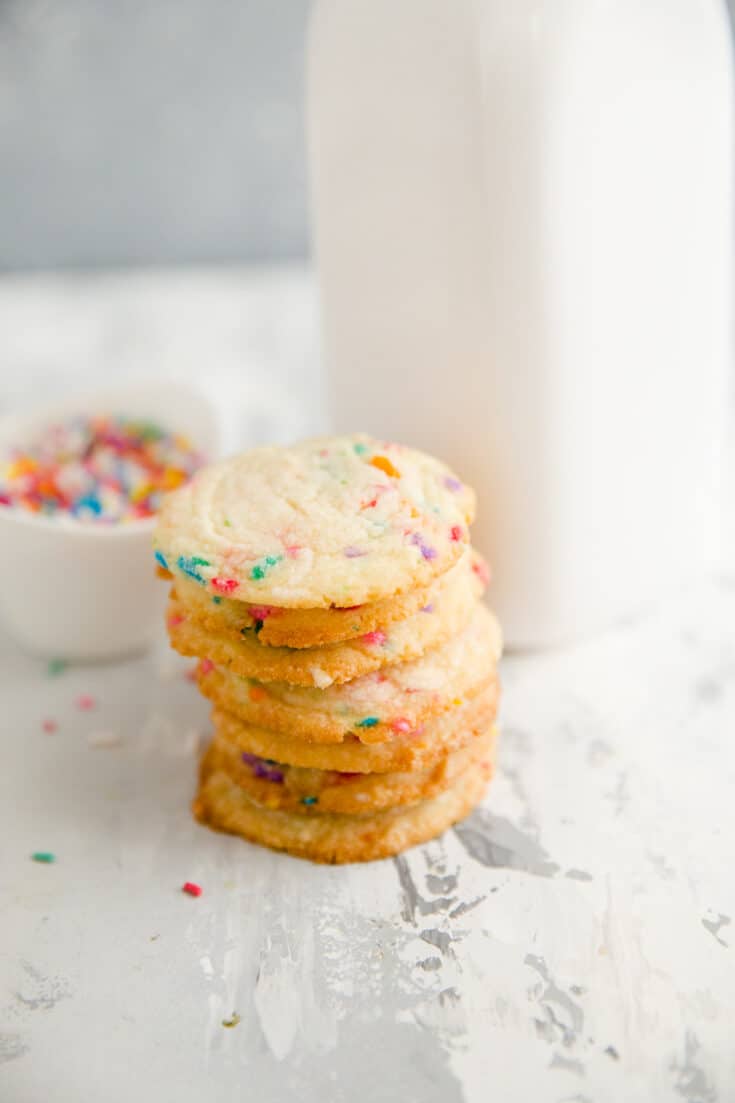 stack of butter cookies next to a milk jar