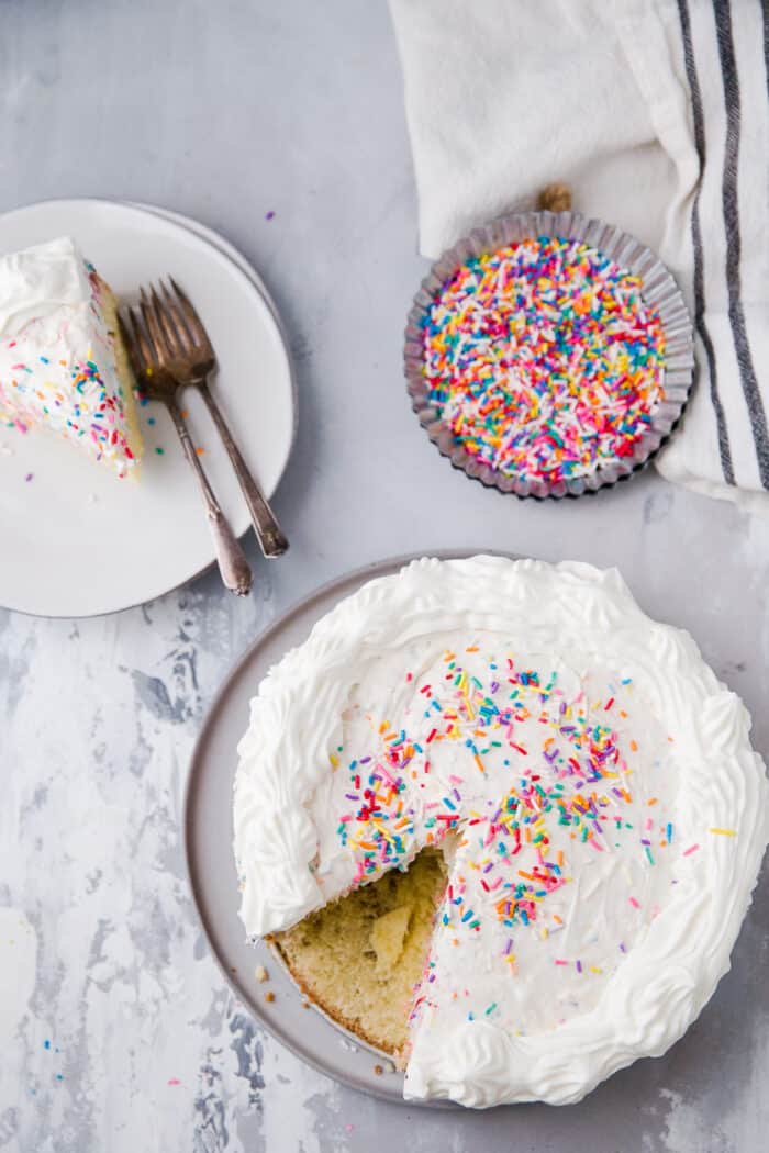 funfetti cake with a piece on a white plate on the side