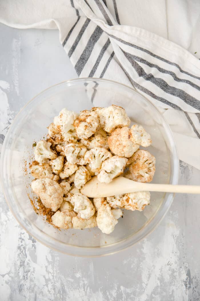 cauliflower in a bowl with oil and seasoning